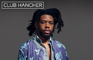 Sean Mason headshot wearing purple floral jacket looking straight on at the camera against a grey background. Club Hancher text treatment in upper left corner